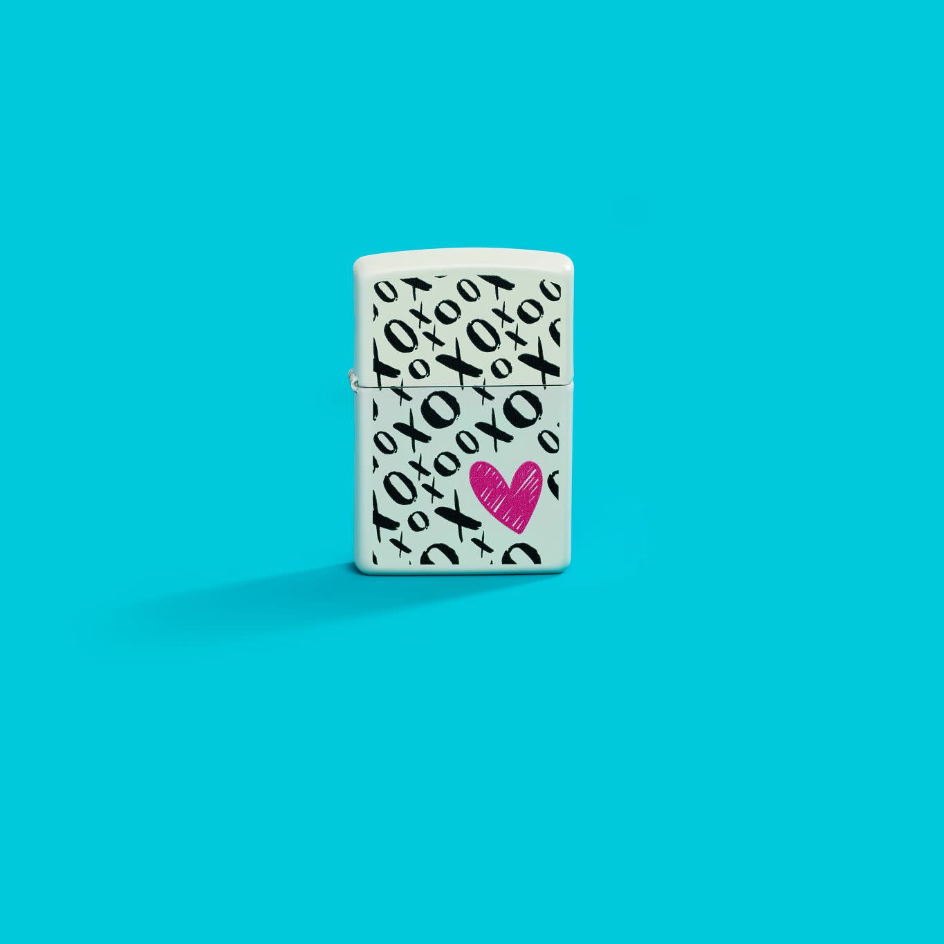 Lifestyle image of Zippo Hugs and Kisses Design White Matte Windproof Lighter in a blue scene.