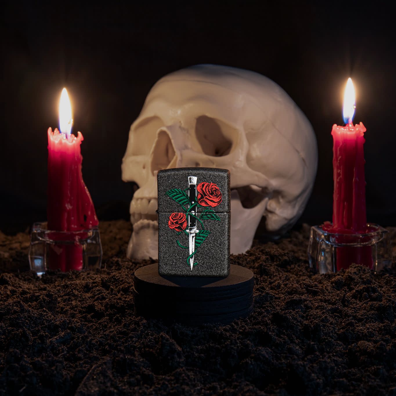 Lifestyle image of Rose Dagger Tattoo Design Black Crackle?? Windproof Lighter standing with a skull and lit candles behind it.