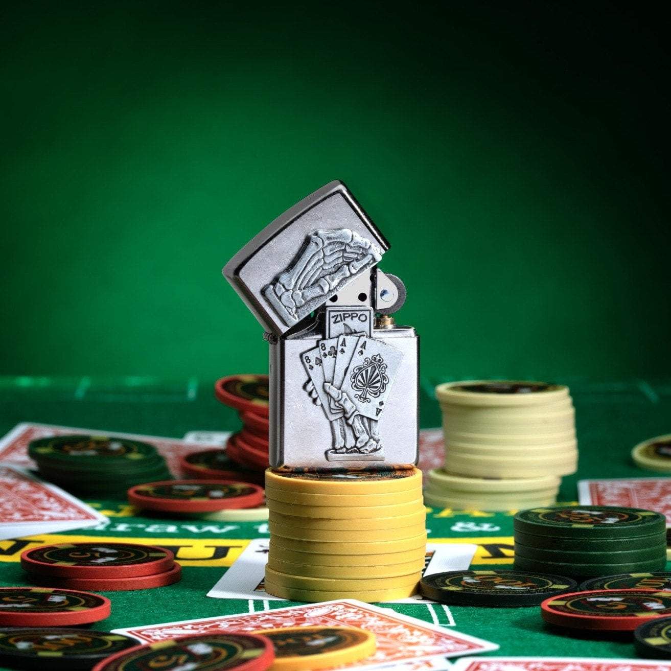 Dead Mans Hand Surprise Emblem Design Street ChromeÆ?⺠Windproof Lighter standing on stacked poker chips, with cards and chips scattered all around a poker table.