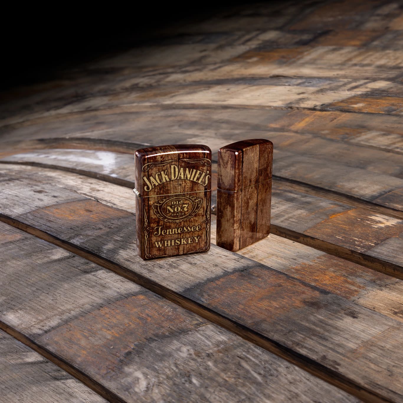 Lifestyle image of Zippo Jack Daniel's?? Barrel Design 540 Tumbled Brass Windproof Lighter standing on a barrel.