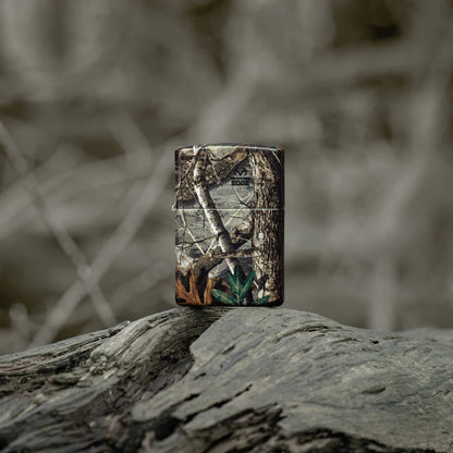 Lifestyle image of Zippo Realtree?? EDGEÆ?âº Camo Design 540 Matte Windproof Lighter standing on a fallen limb in a wooded scene.