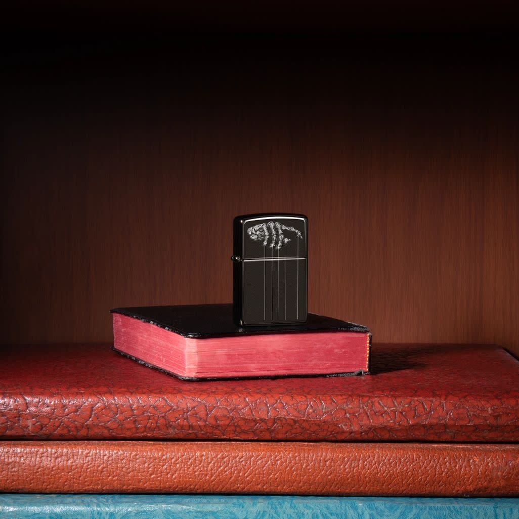 Lifestyle image of Dragon Fruit Design Mercury Glass Windproof Lighter standing in a book case on books