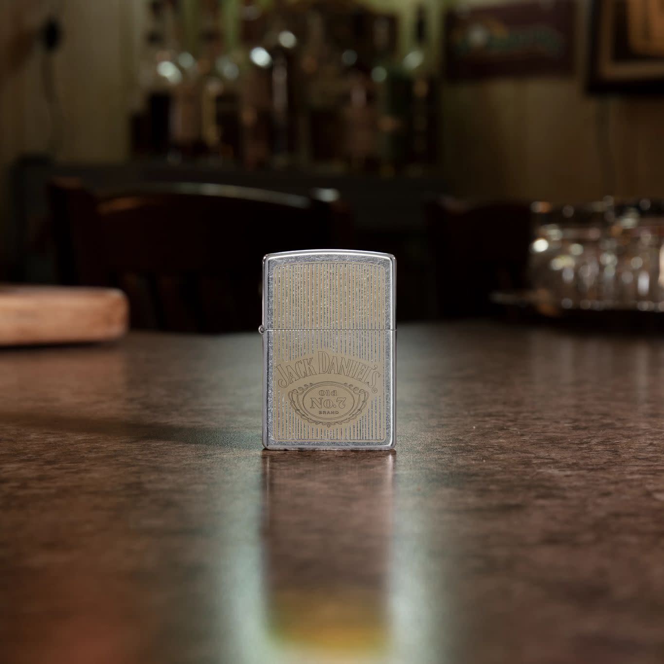 Lifestyle image of Jack Daniel's?? Logo Street ChromeÆ?âº Windproof Lighter standing on a bar.