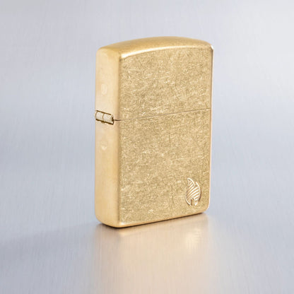 Lifestyle image of Zippo Armor?? Series Flame Tumbled Brass Windproof Lighter on a light gray background.